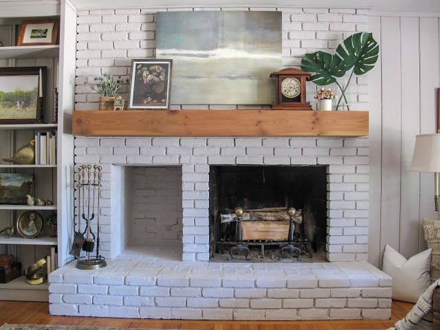 a living room with a white brick fireplace and bookshelves filled with pictures on the wall