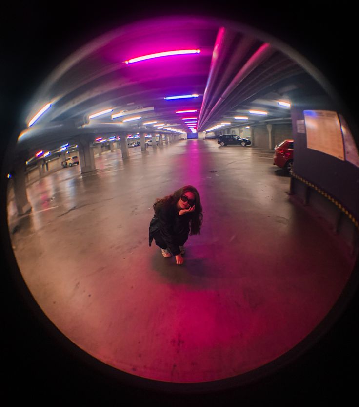 a woman is standing in the middle of an empty parking garage