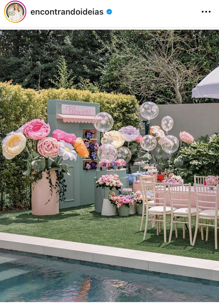 an outdoor party with balloons and flowers on the grass next to a small swimming pool