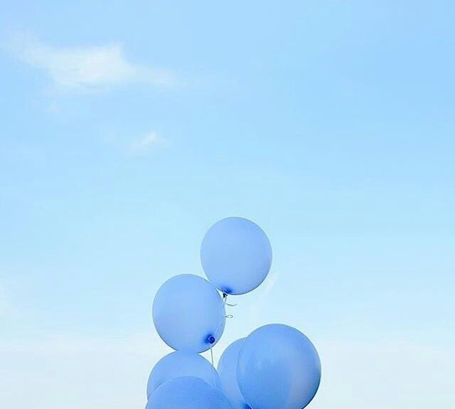 several blue balloons floating in the air