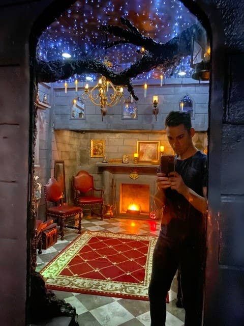 a man standing in front of a fire place holding a cell phone and looking at it