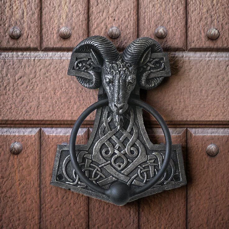 an ornate door knockle with a ram head on it