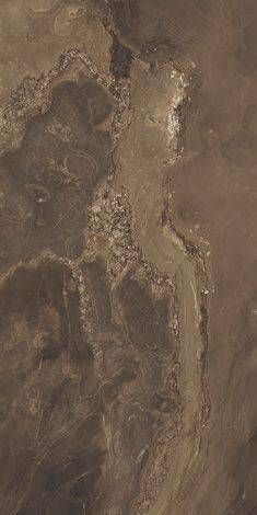 an aerial view of the desert with brown and white rocks, dirt patches and trees