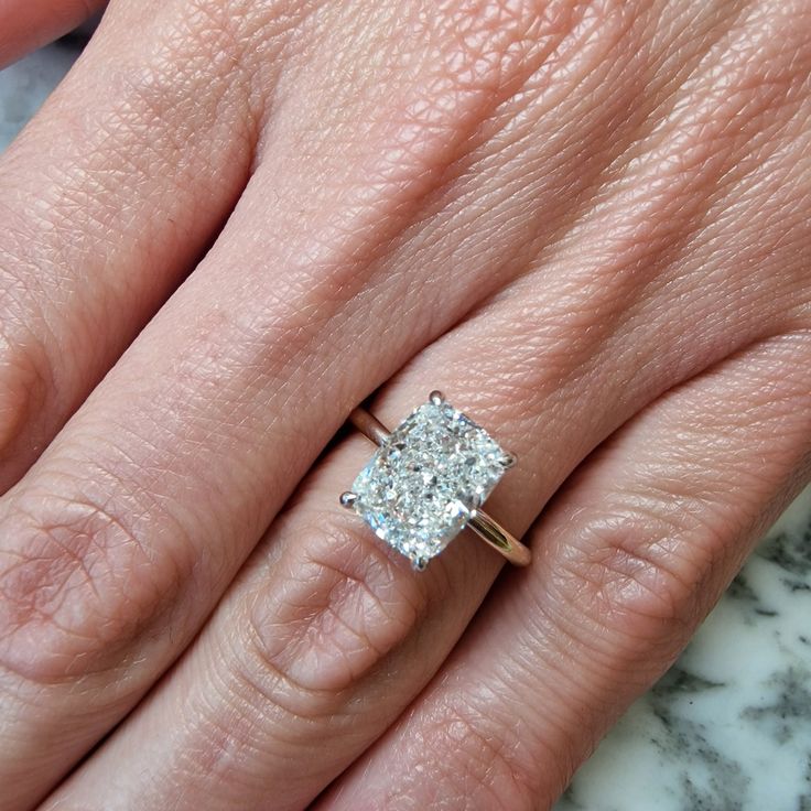 a woman's hand with a diamond ring on top of her finger and an engagement band