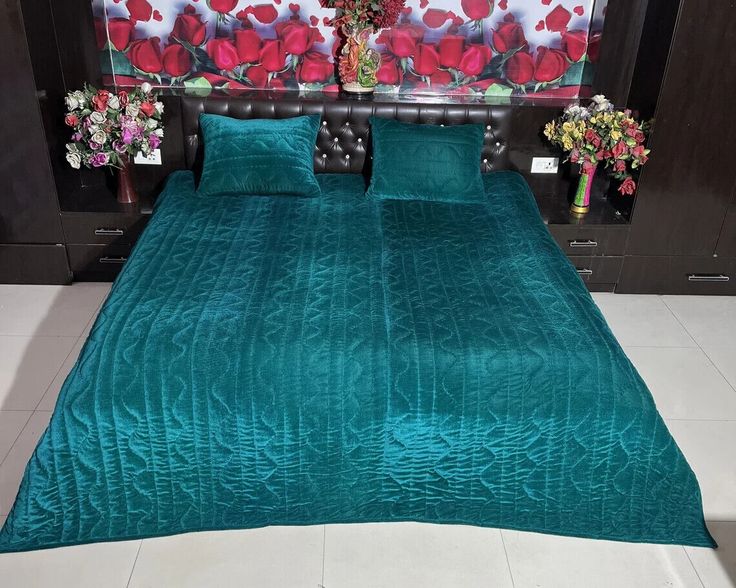 a bed with green comforter and pillows in front of a floral wallpapered headboard