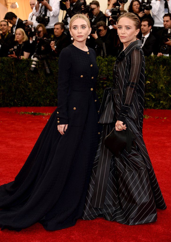 two women in black dresses standing next to each other on the red carpet at an event