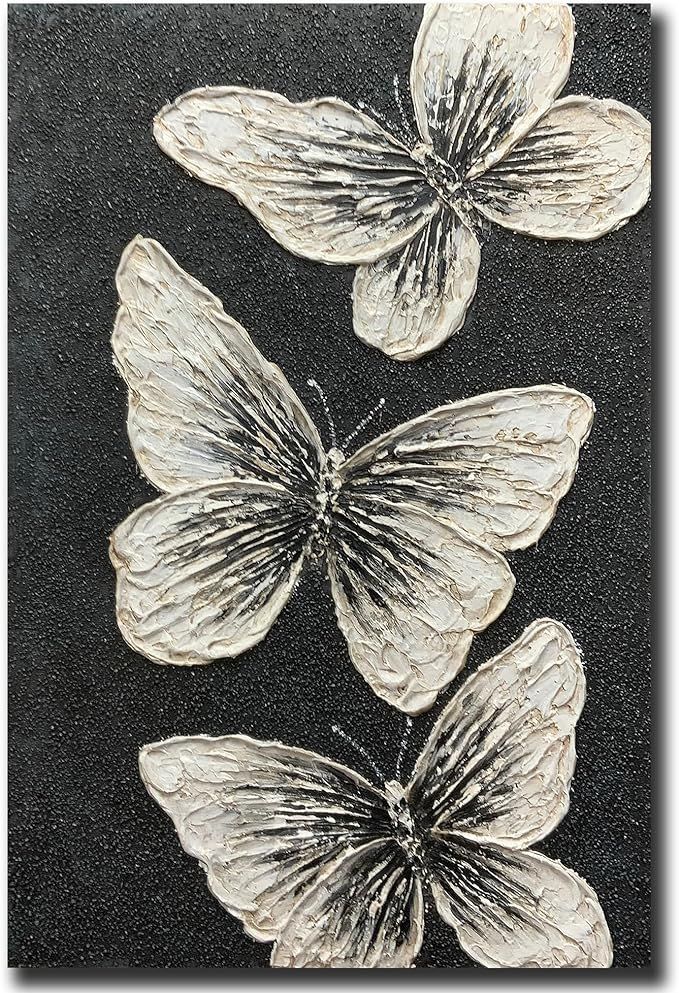 three white butterflies sitting on top of a black surface