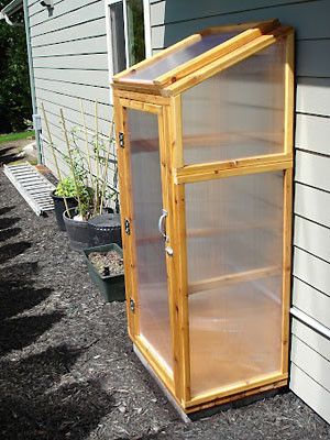 a small wooden greenhouse on the side of a house