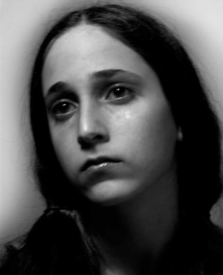 a black and white photo of a woman's face looking at the camera with an intense look on her face