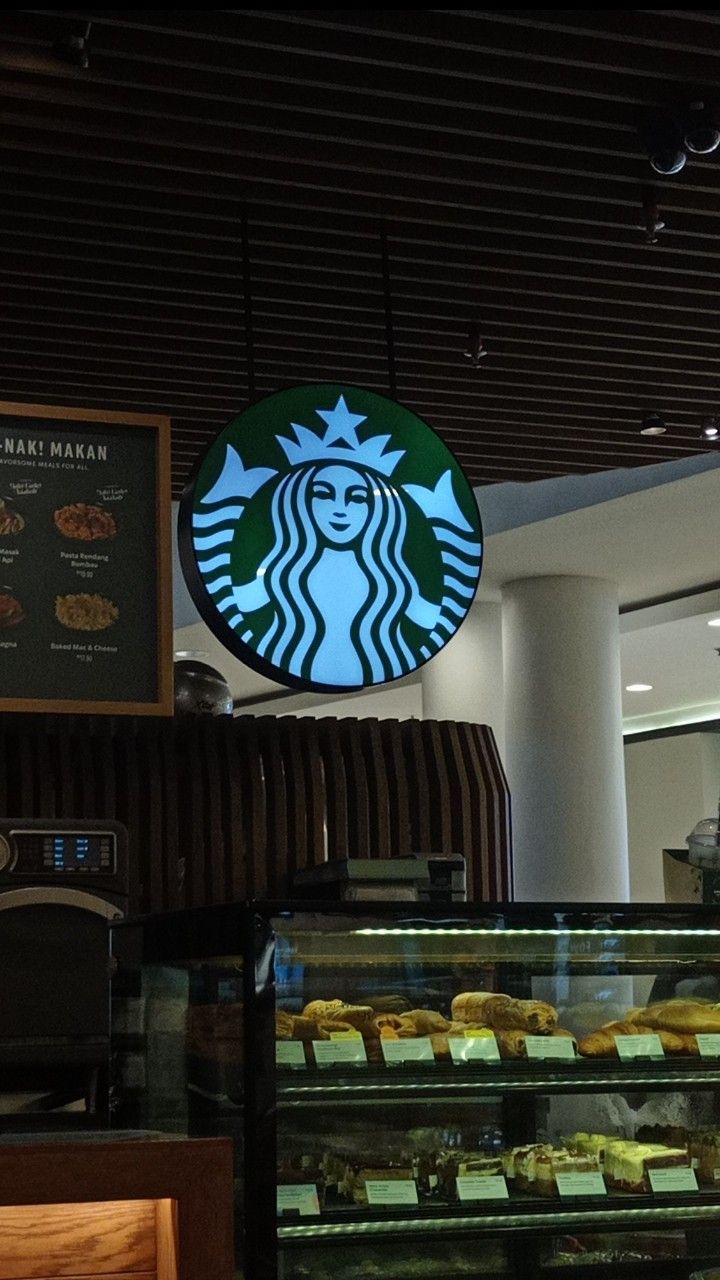 a starbucks sign above a display case filled with pastries