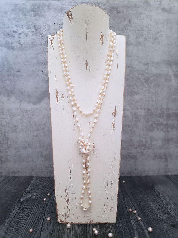 Ivory Pearl Necklace Shimmery and shiny semi-baroque pearls will charm you in this extra-long Ivory pearl necklace, which can be worn in an infinity of ways. The oval, semi-baroque pearls are hand-knotted onto a silk cord, a traditional way of showcasing pearls. Knotting makes necklaces stronger and also allows for a beautiful drape while at the same time protecting each pearl from rubbing up against the next. No worries about chasing beads around the floor with this necklace should it ever brea Elegant Single Strand Pearl Long Necklace, White Baroque Pearl Long Necklace, Pearl White Long Pearl Necklace In Elegant Style, Elegant Pearl White Long Pearl Necklace, Elegant Pearl White Long Necklace, White Baroque Pearl Lariat Necklace, Wedding Long Baroque Pearl Necklace, Pearl White Pearl Lariat Necklace, White Lariat Pearl Necklace