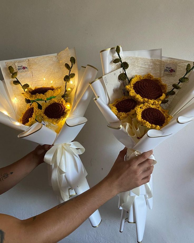 two bouquets of sunflowers are being held up by someone's hand