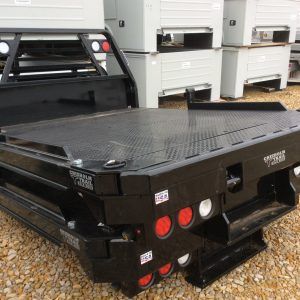 the back end of a black truck parked in gravel next to other white boxes and bins