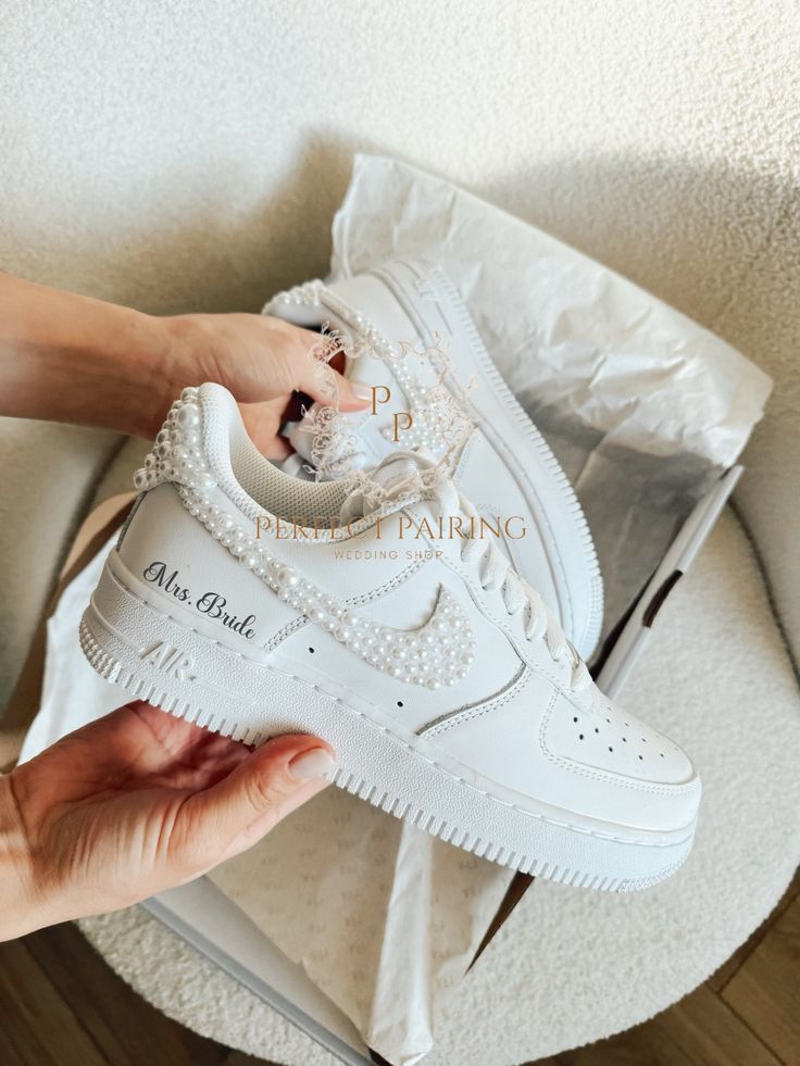 a person holding up a white nike air force shoe with pearls on the soles