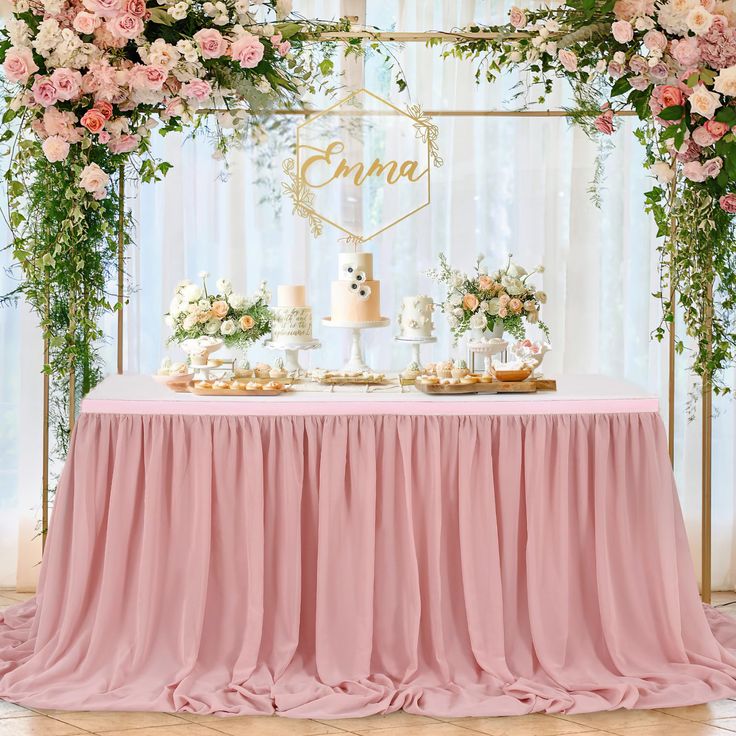 a table topped with cakes and desserts under a floral covered arch filled with flowers