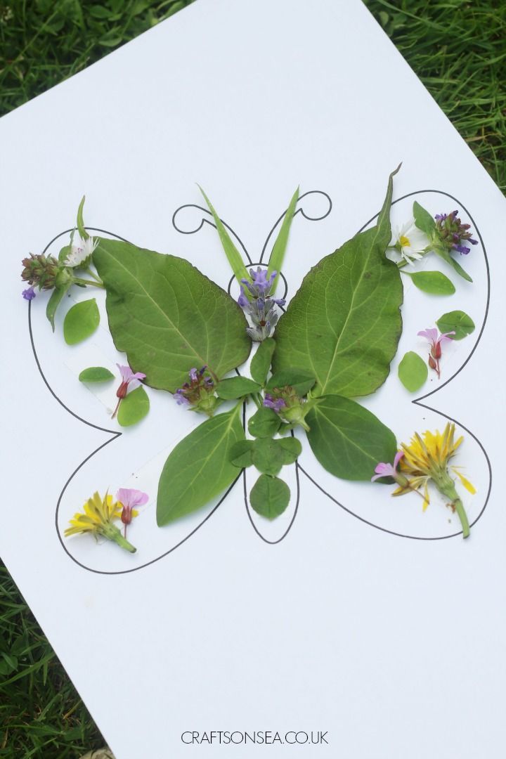 a butterfly made out of leaves and flowers sitting on top of a piece of paper