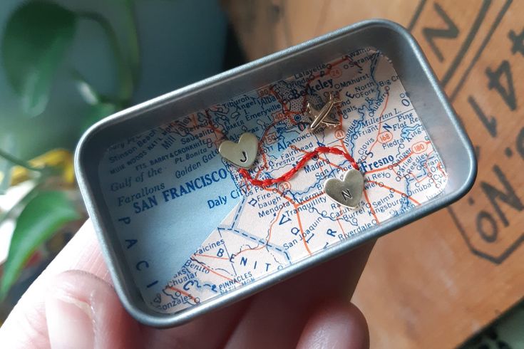 someone is holding up a tiny map with hearts on it