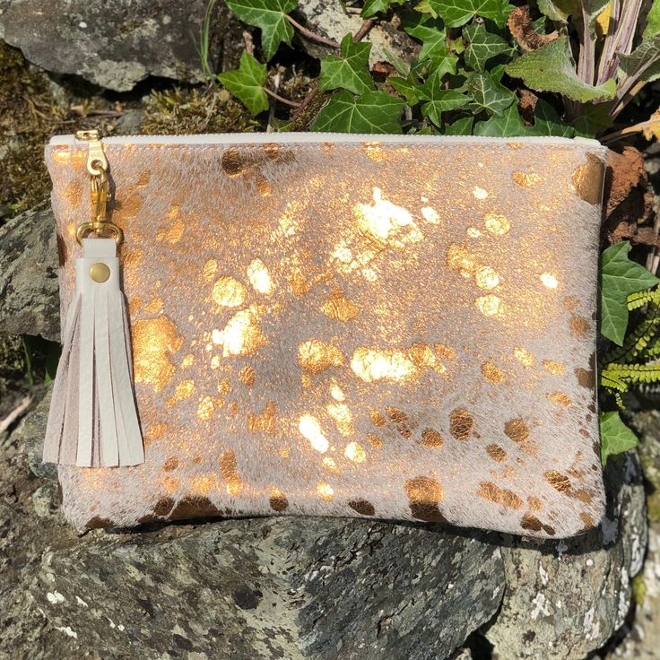 This Breccia clutch is a beautiful bag that is great for so many occasions, or for use everyday with style! Dimensions: Height: 18cm (7.08in) Width: 24cm (9.4in) Flat construction It is made from hair on cowhide in metallic bronze on the front with soft, cream leather on the back or you can choose cowhide on both sides - please see the Material options below.  The Breccia has a cotton, light fawn lining with gold stars and a handy credit card sized pocket inside. It has  a pretty YKK gold colour Cowhide Clutch, Gold Clutch Bag, Gold Clutch, Gold Bag, Gold Leather, Gold Stars, Beautiful Bags, Inside Pocket, Evening Bags