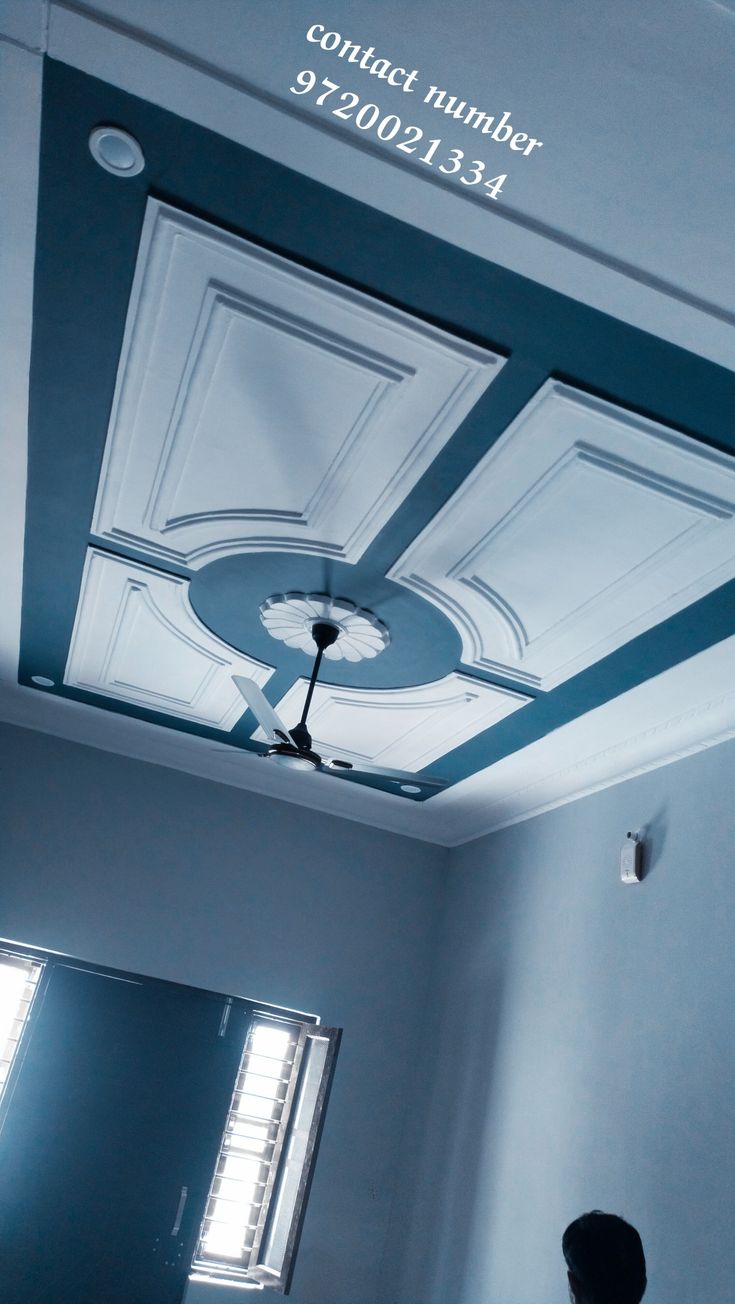 a man standing in front of a ceiling with a fan on it's side