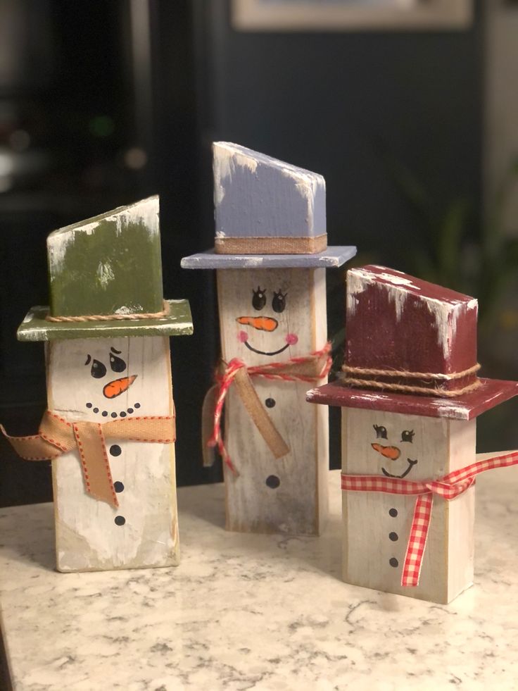 three snowmen made out of wooden blocks on a counter