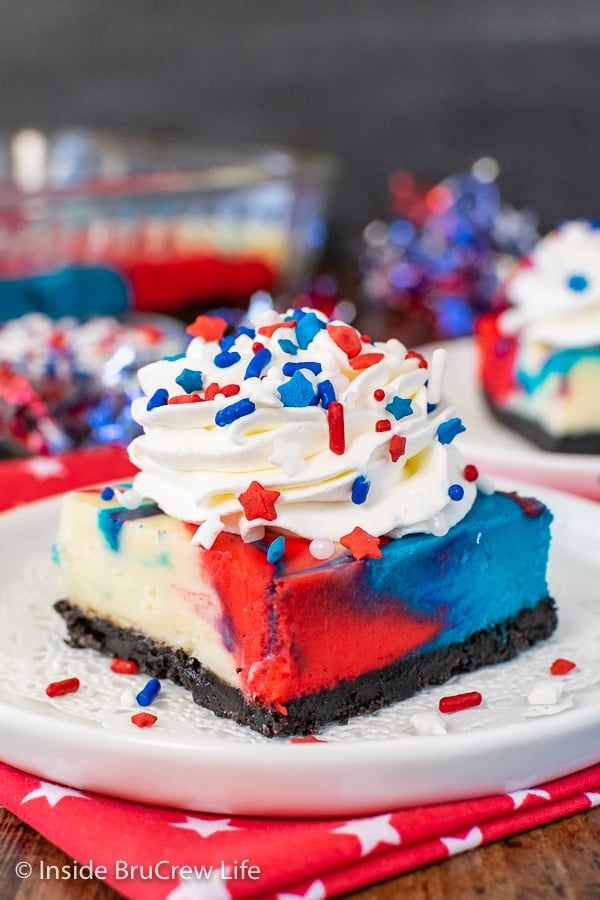 a slice of patriotic cheesecake on a white plate with red, white and blue sprinkles