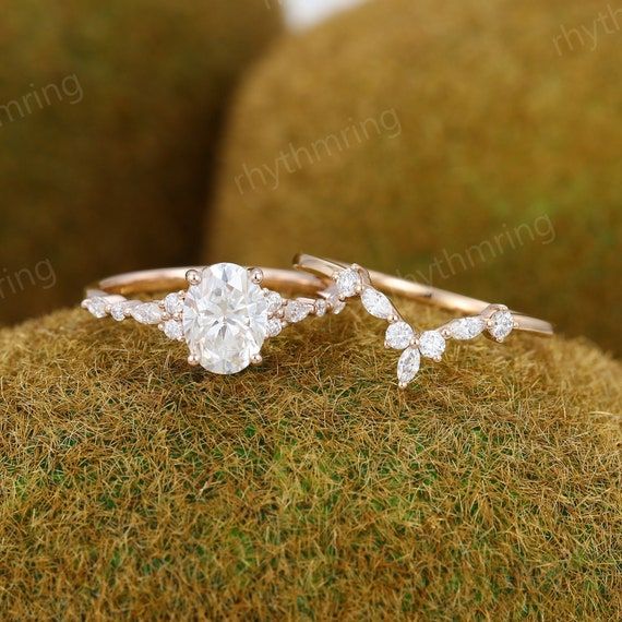 two engagement rings sitting on top of a moss covered surface