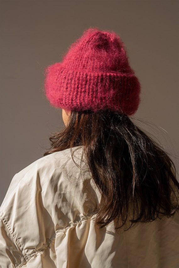 a woman wearing a pink knitted hat looking down at the back of her head