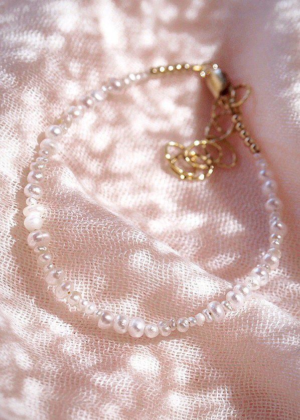 This tiny luminous white freshwater pearl bracelet is a must have staple. The organic ensemble of varying sized pearls make each bracelet one of a kind. Wear this gold pearl bracelet to remind yourself of the soothing sands of Hawaii.✦ DETAILS ✦✧ Name: Kale'a (kah LEH ah) - joy.✧ Adjustable Length from 6.5"-8".✧ White 2-4mm Freshwater Pearls.✧ 18kt Gold Filled with lobster clasp.✧ All Ke Aloha Jewelry pieces come packaged thoughtfully, beautifully, and ready for gift giving.✧ Unless otherwise no Adjustable Pearl Bracelet With Pearl Chain, Handmade Dainty Pearl White Bracelets, Handmade Delicate Pearl Bracelets, Delicate Handmade Pearl Bracelets, Delicate Baroque Pearl Bracelet With Pearl Chain, Delicate Baroque Pearl Chain Bracelet, Delicate Baroque Pearl Bracelet, Delicate Pearl Bracelet With Tiny Beads As Gift, Delicate Tiny Beads Pearl Bracelet As Gift