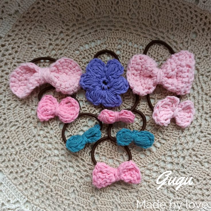 several crocheted bows and hair clips are arranged on top of a doily