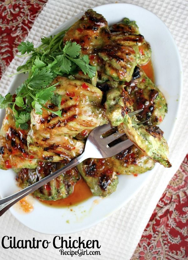 a white plate topped with meat covered in sauce and garnished with cilantro