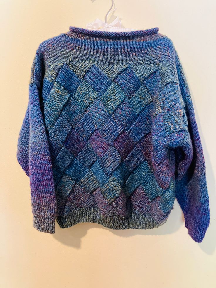 a blue and purple sweater hanging on a white wall