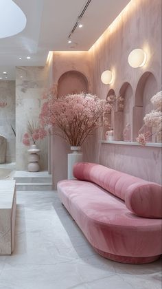 a living room filled with pink furniture and flowers in vases on either side of the couch