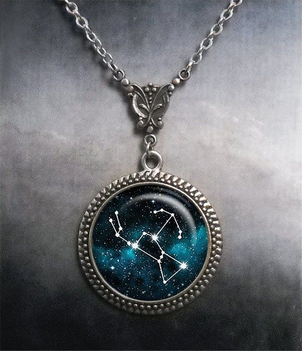 a necklace with the zodiac sign on it and stars in the sky behind it, hanging from a silver chain