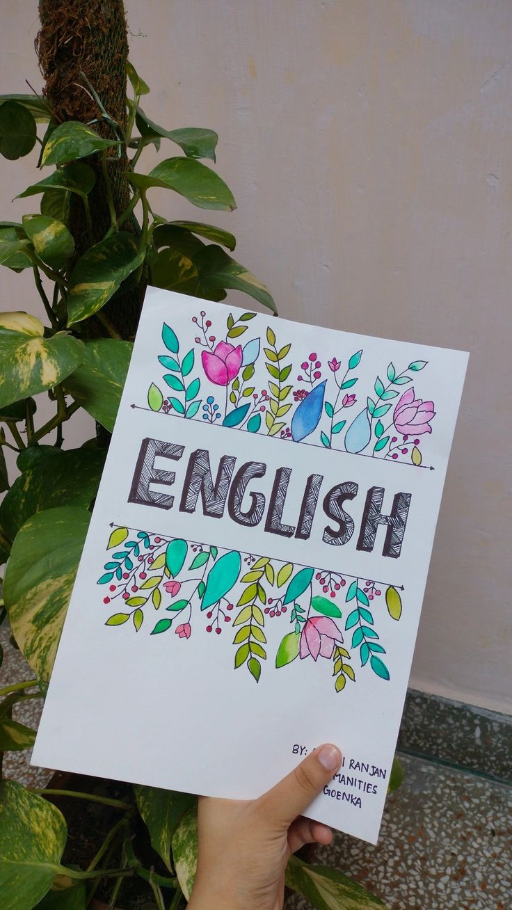 a person holding up a sign that says english in front of some plants and flowers