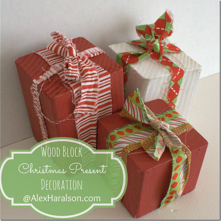 three wrapped presents sitting next to each other on top of a white table with the words wood block christmas present decoration