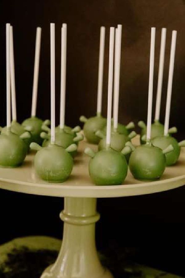 green cake pops with white sticks sticking out of them sitting on a plate in front of a black background