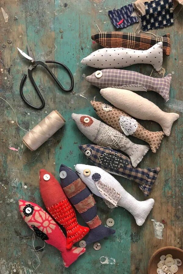 several different types of fabric fish on a table with scissors and thread spools