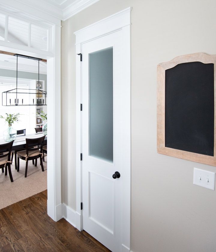 an empty dining room with a chalkboard hanging on the wall next to a white door