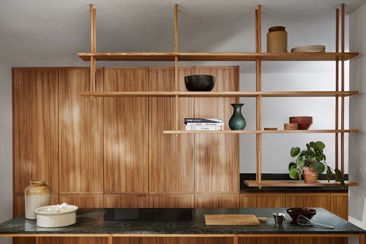 a kitchen with wooden shelving and black counter top next to a potted plant