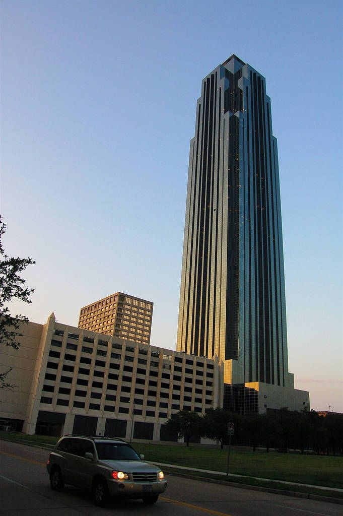 a car driving down the road in front of a tall building