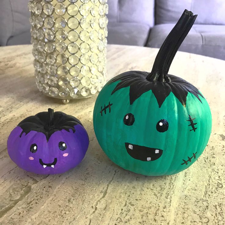 two painted pumpkins sitting on top of a table