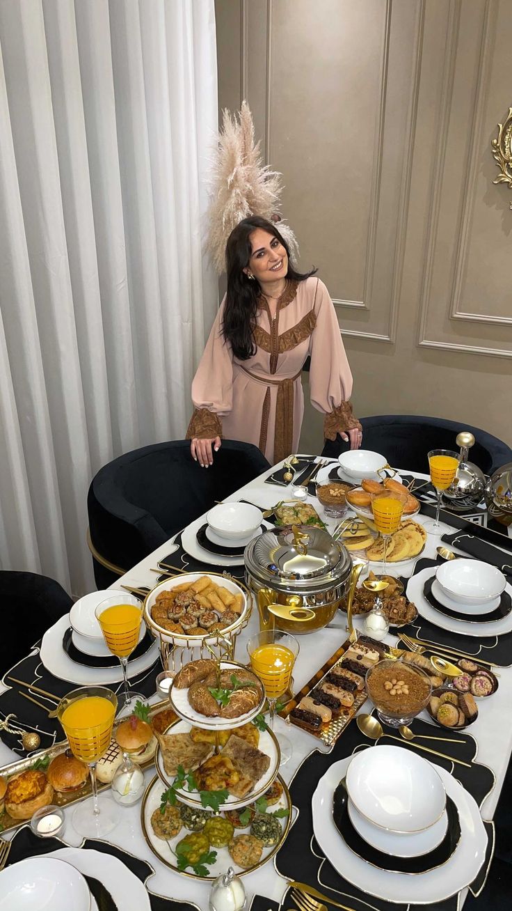 a woman standing in front of a table filled with plates and bowls full of food