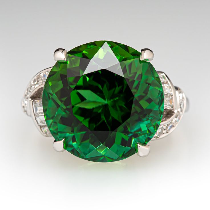 an emerald colored ring with diamond accents