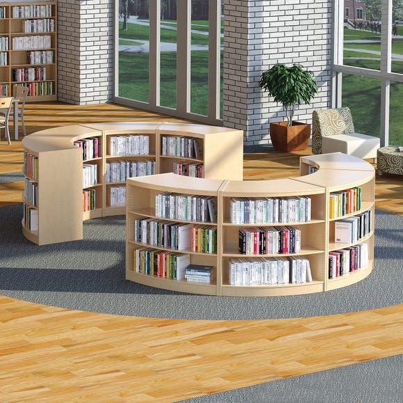 a library with several bookshelves and tables in the center, along with two couches