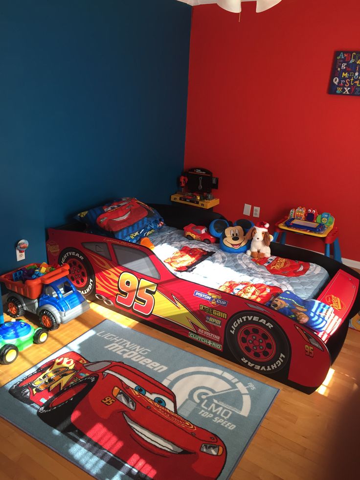 a child's bedroom with cars bedding and rugs