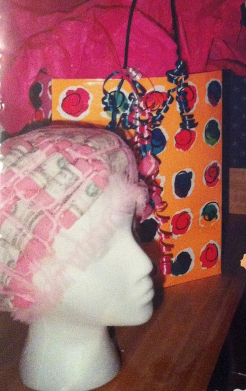 a mannequin's head wearing a pink hat next to an orange bag