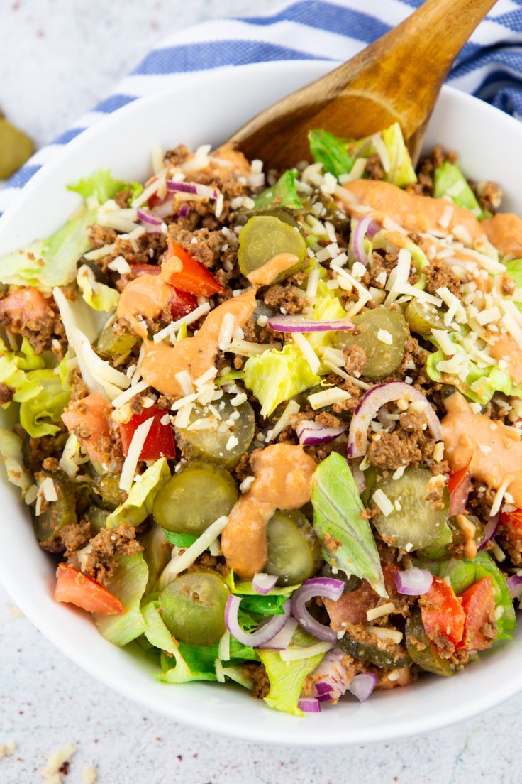 a white bowl filled with salad and dressing on top of a blue and white towel