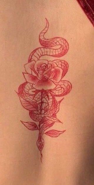 a woman's back with a snake and rose tattoo on her left side ribcage