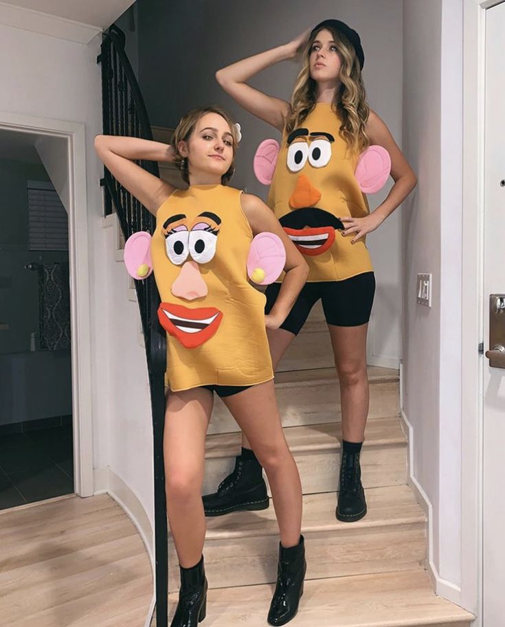 two women in matching outfits are standing on the stairs with their hands behind their backs