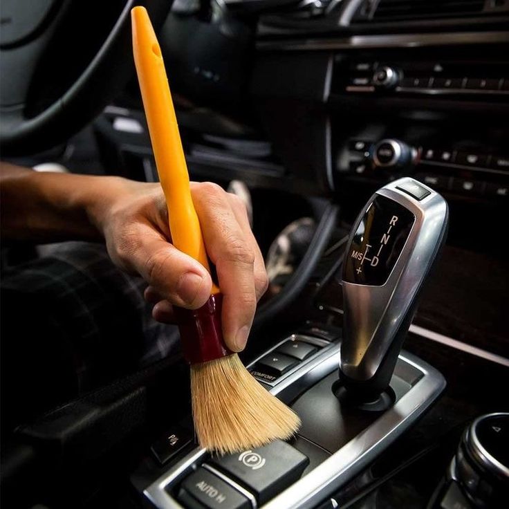 a person holding a brush in their hand while sitting in a car with steering wheel controls